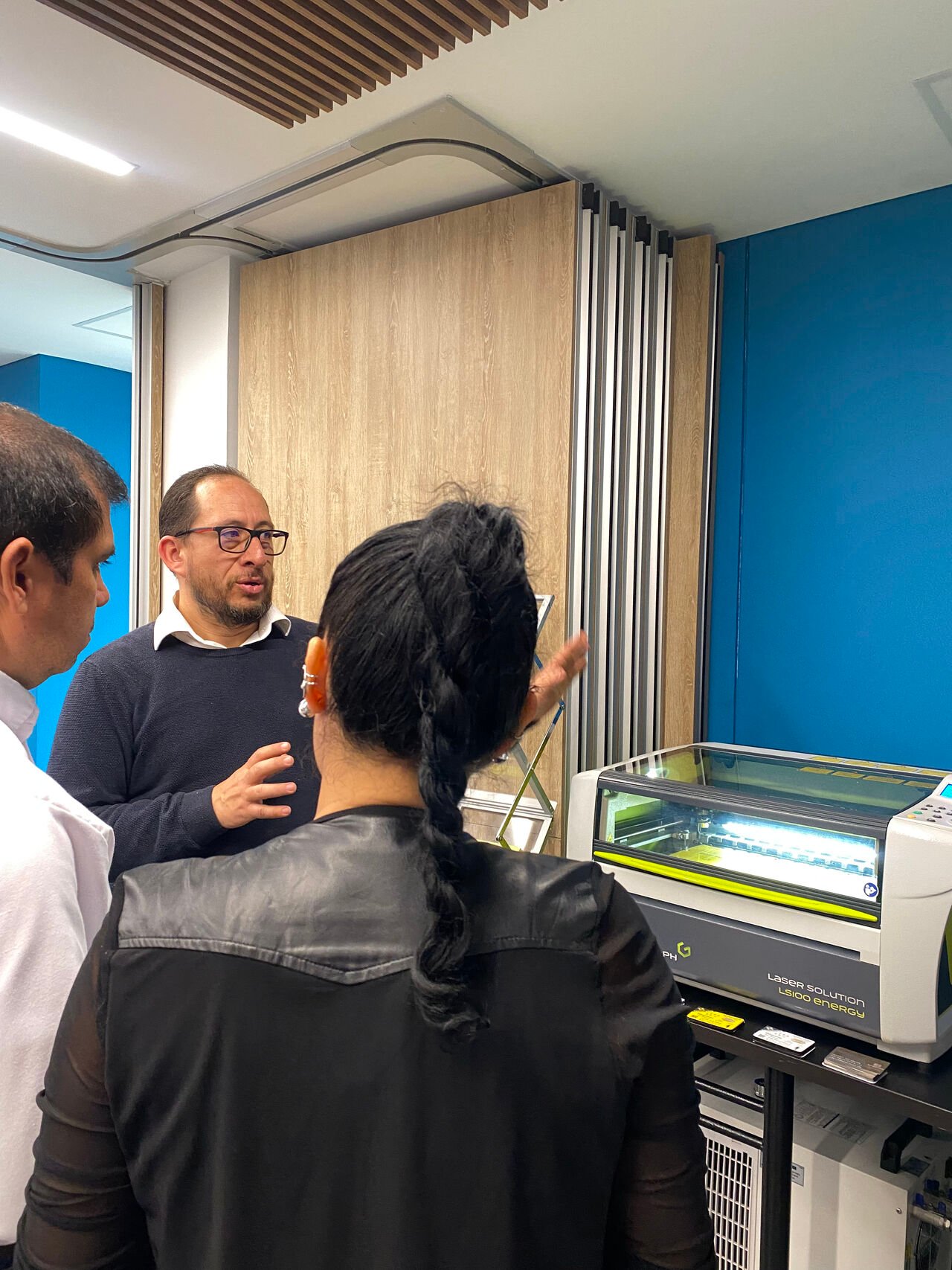 Equipo de Mecatronisis en su showroom de Bogotá junto a una máquina láser Gravotech y muestras de placas grabadas